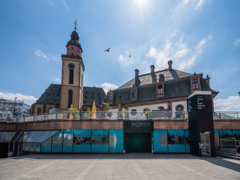 Fassade des MOMEM mit Vorplatz, Eingang und Hauptwache sowie Katharinenkirche im Hintergrund