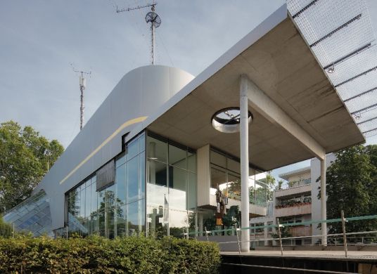 Eingang zum Museum für Kommunikation mit Büschen im Vordergrund und umgebenden Bäumen