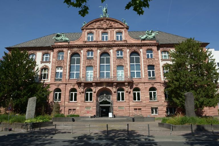 Fassade mit Eingangsbereich zum Altbau des Senckenberg Naturmuseum mit Bäumen an den Seiten und Skulpturen auf dem Dach